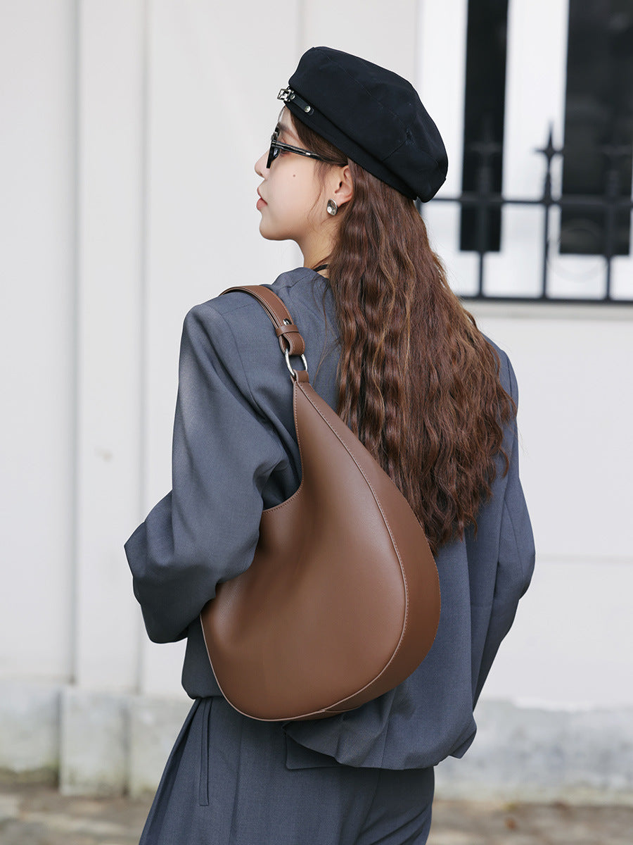 Brown crescent leather shoulder bag worn on the shoulder
