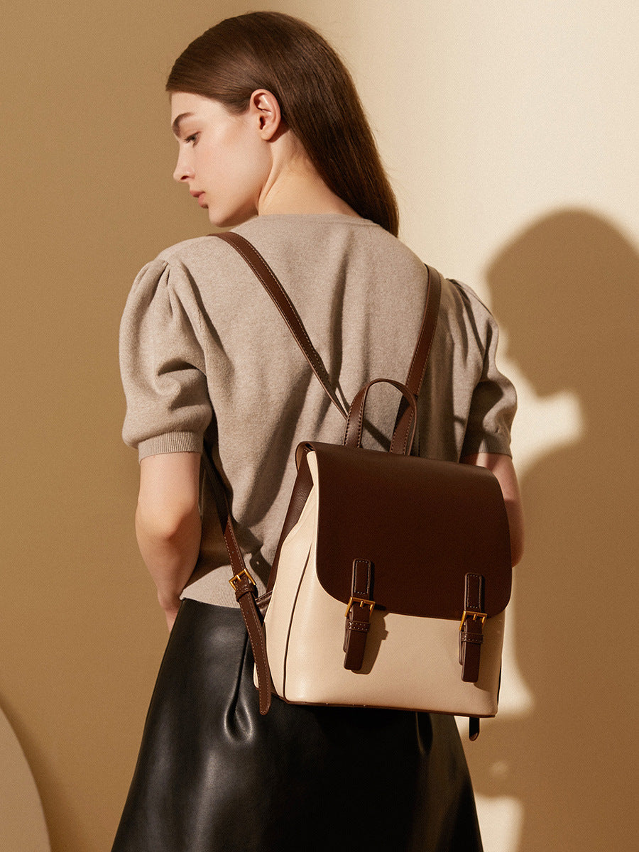 Backpack worn on both shoulders by a model in a beige top, showing the adjustable straps from behind