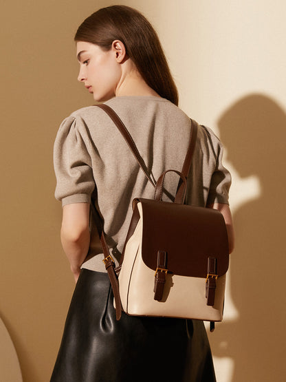Backpack worn on both shoulders by a model in a beige top, showing the adjustable straps from behind