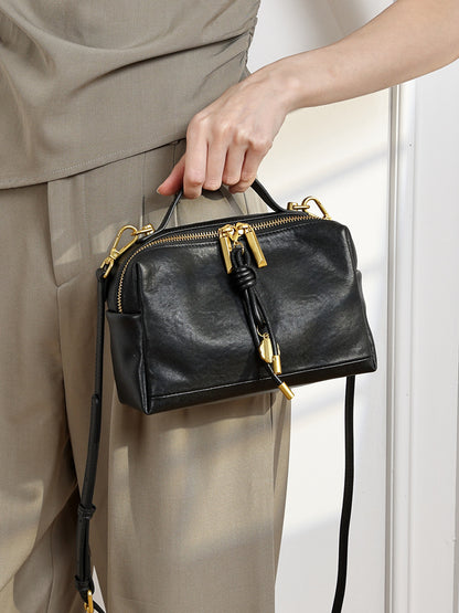 Black cowhide leather crossbody bag carried by hand in lifestyle photo