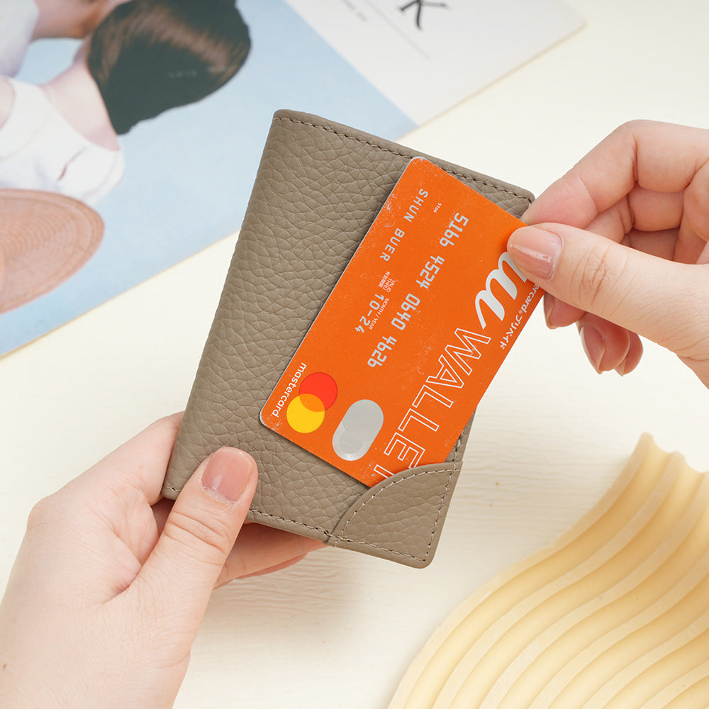 Hands holding a grey cowhide card holder and inserting an orange card