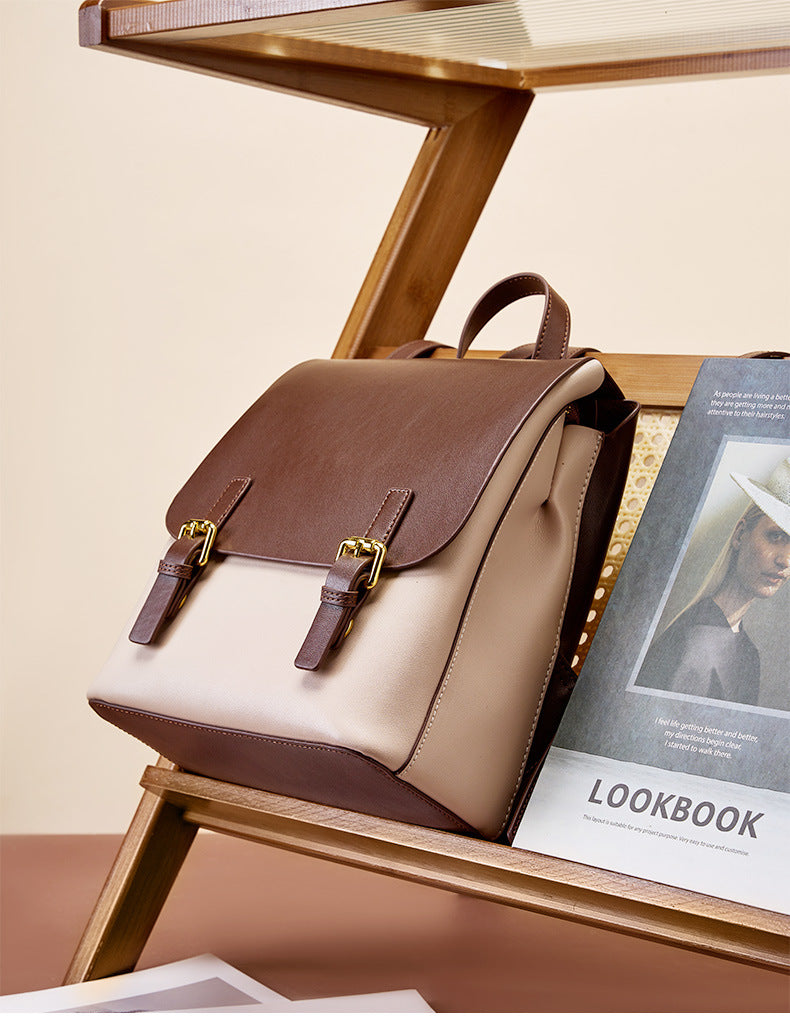 Two-tone backpack resting on a wooden folding chair next to a lookbook magazine
