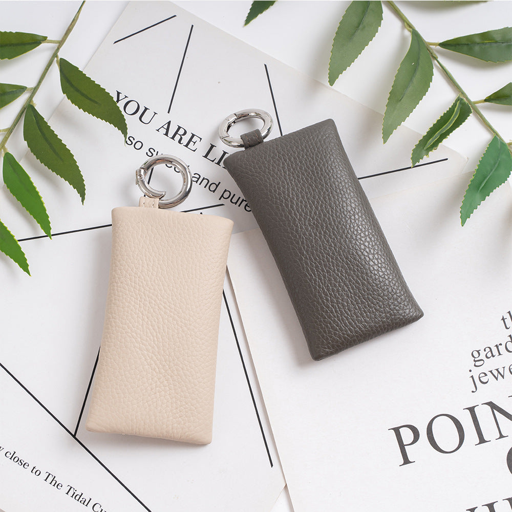Light gray and dark gray leather key pouches styled flat on a printed paper background