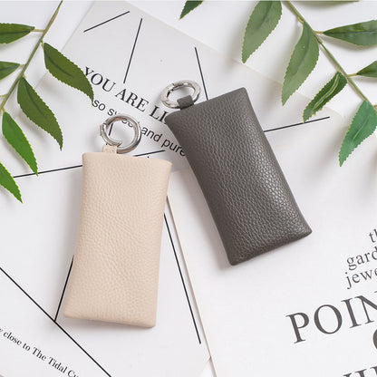 Light gray and dark gray leather key pouches styled flat on a printed paper background