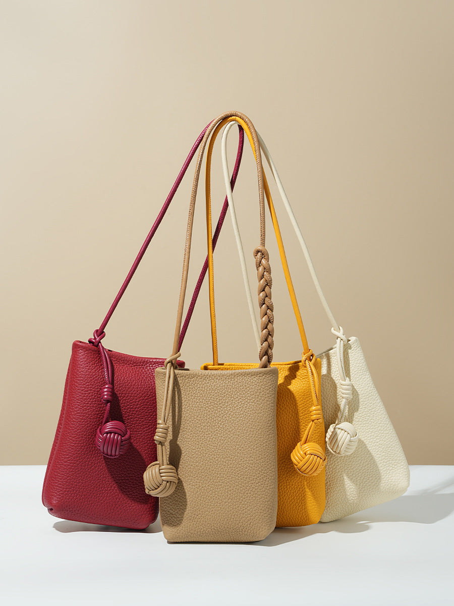 Color lineup of red, beige, yellow, and white pebbled leather mini bucket phone bags together