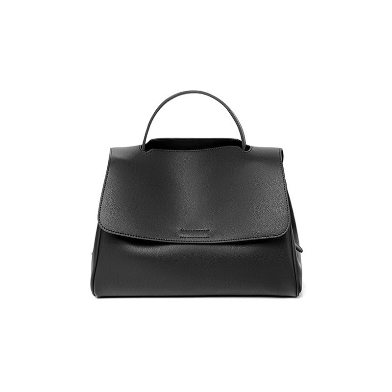 Black cowhide leather top-handle bag with flap closure on white background