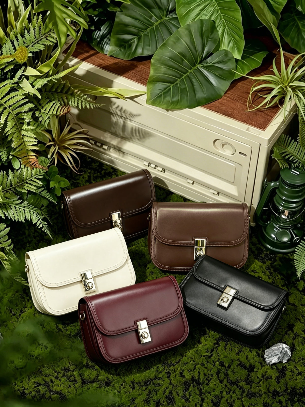 Five colorways of cowhide leather messenger bags displayed on moss