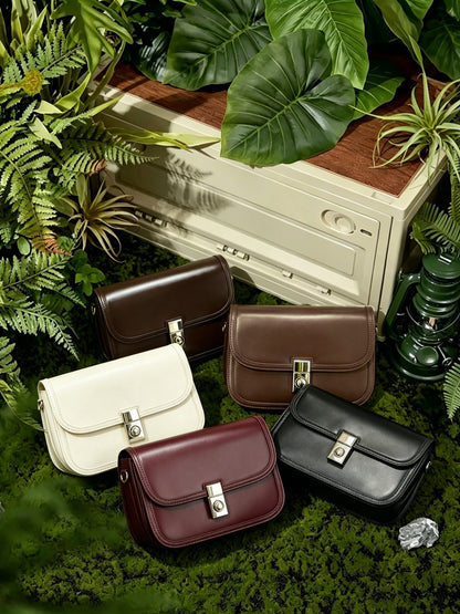 Five colorways of cowhide leather messenger bags displayed on moss