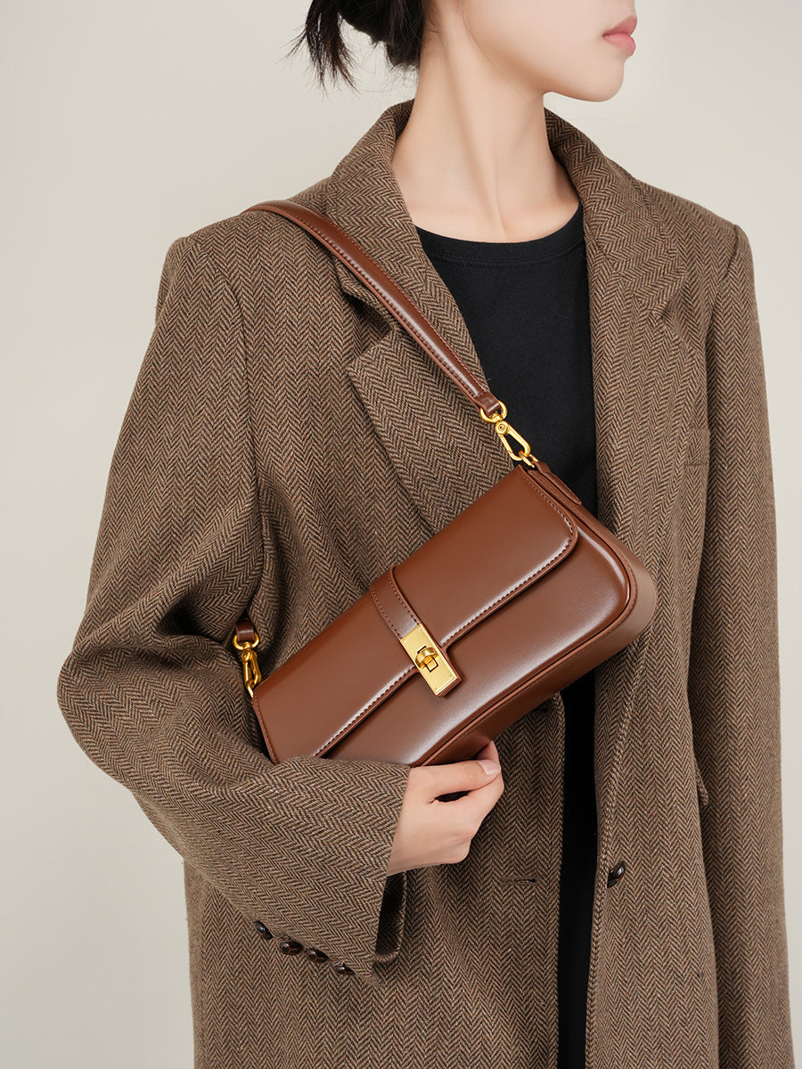 Model wearing a coffee brown leather mini shoulder bag crossbody with a tailored herringbone coat