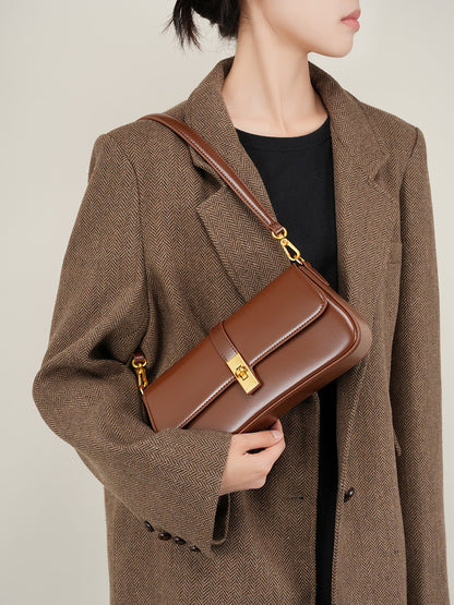 Model wearing a coffee brown leather mini shoulder bag crossbody with a tailored herringbone coat