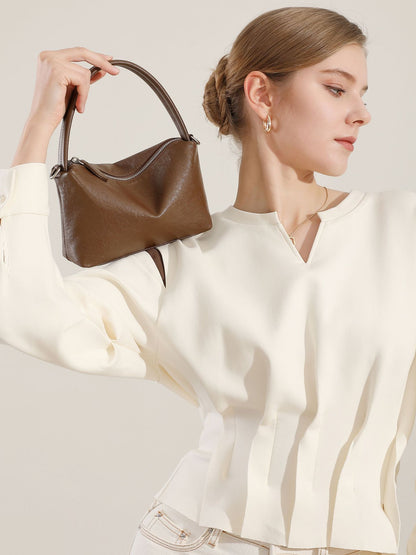 Brown leather pillow bag held up high by a model