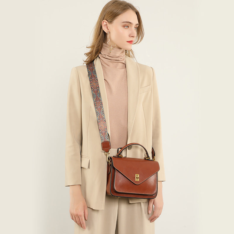 Woman in beige suit wearing brown leather messenger bag crossbody with patterned strap