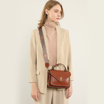 Woman in beige suit wearing brown leather messenger bag crossbody with patterned strap