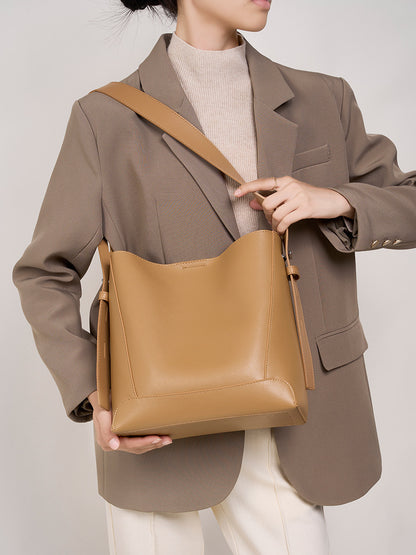 Model holding Golden Brown bucket bag with blazer