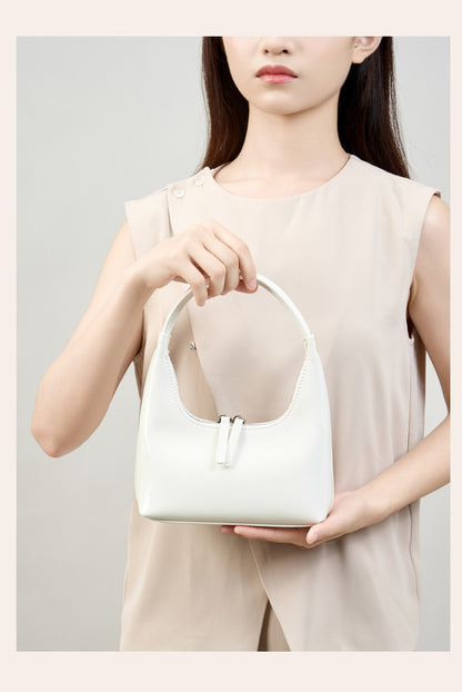 Model holding cream mini hobo bag by the top handle