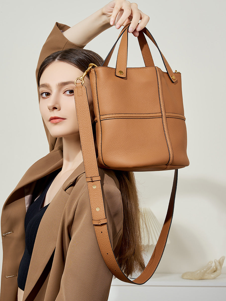 Model lifting brown bucket bag showing its structured shape