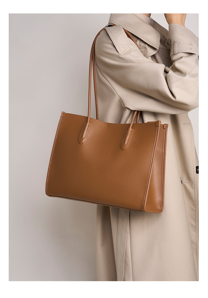 Golden brown leather tote bag styled with a neutral trench coat look