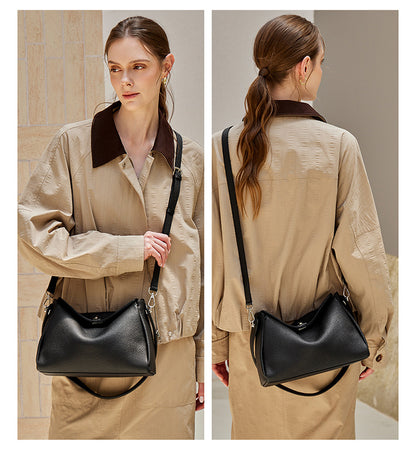 Front and back model shots of a black pebbled leather crossbody bag worn on a beige trench coat