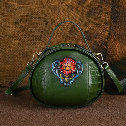 Green cowhide round bag with detachable strap and floral motif