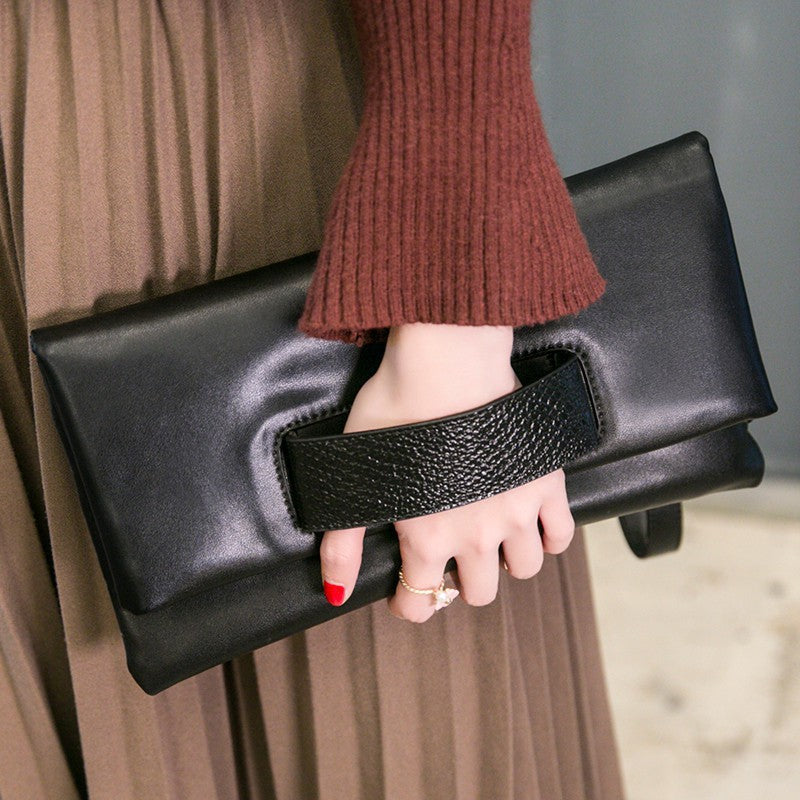 Black envelope clutch with black textured accent panel in a lifestyle view