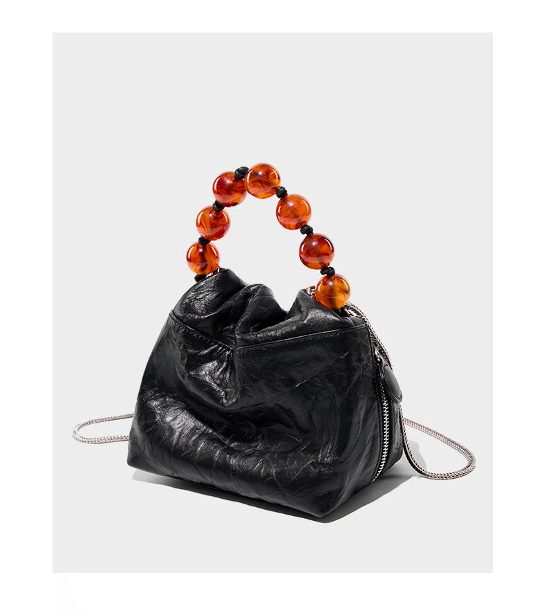 Black crinkle cowhide bag with amber bead handle displayed at angle