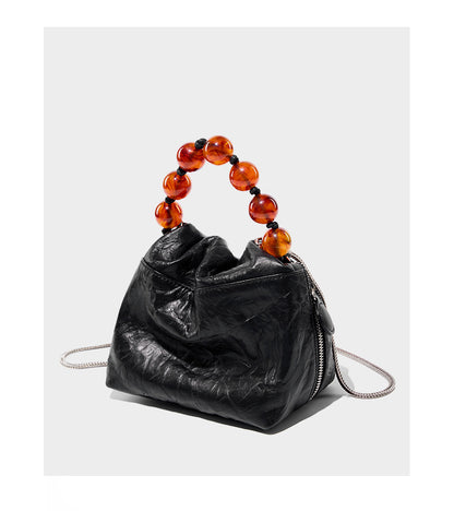 Black crinkle cowhide bag with amber bead handle displayed at angle