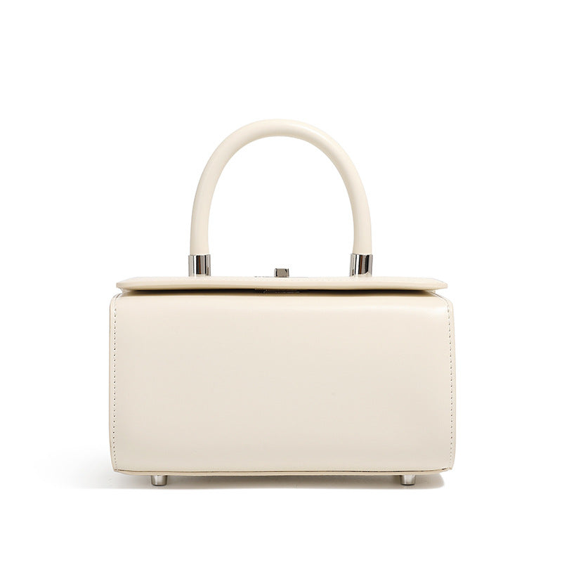 Cream cowhide leather box handbag with rounded top handle on white background
