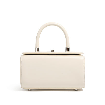 Cream cowhide leather box handbag with rounded top handle on white background