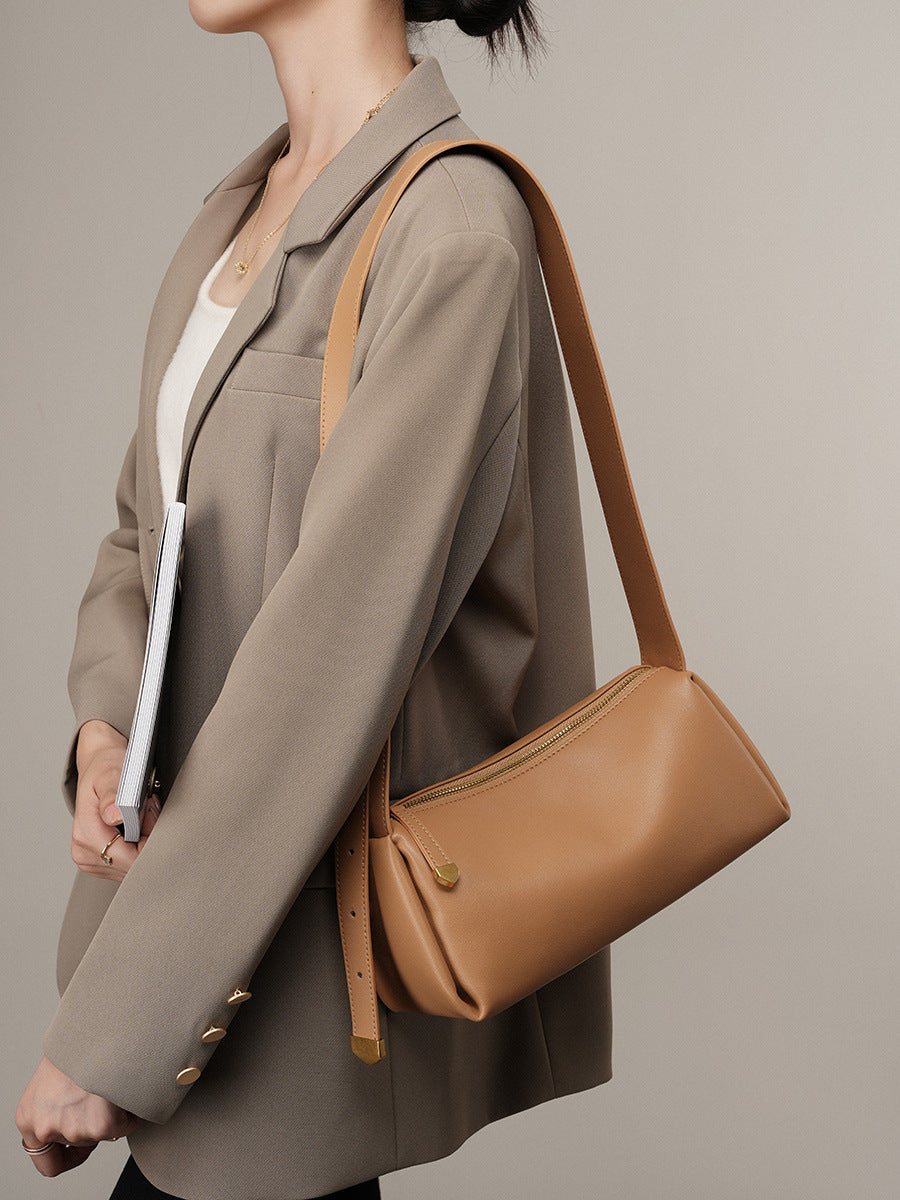 Apricot pillow crossbody bag worn on the shoulder with a beige blazer