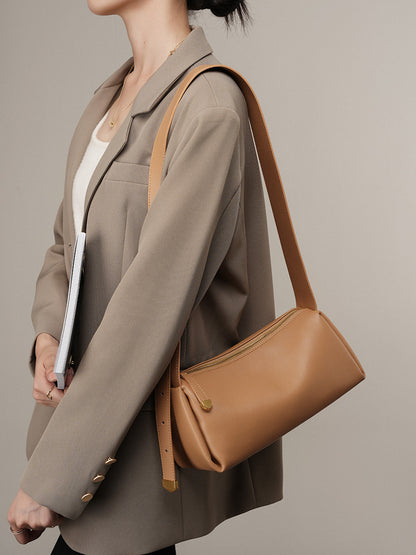 Apricot pillow crossbody bag worn on the shoulder with a beige blazer