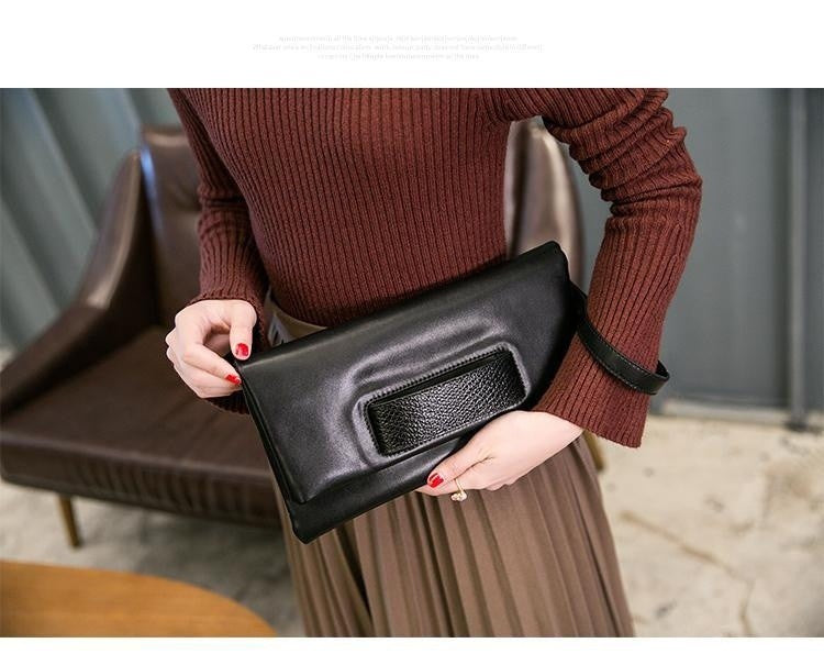 Model carrying a black clutch with textured black accent panel
