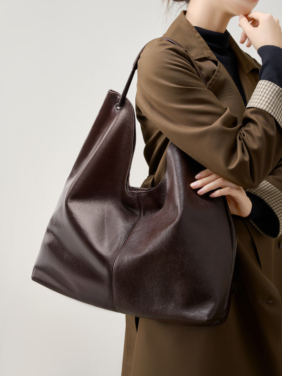 Brown hobo tote bag carried under the arm with a brown trench coat