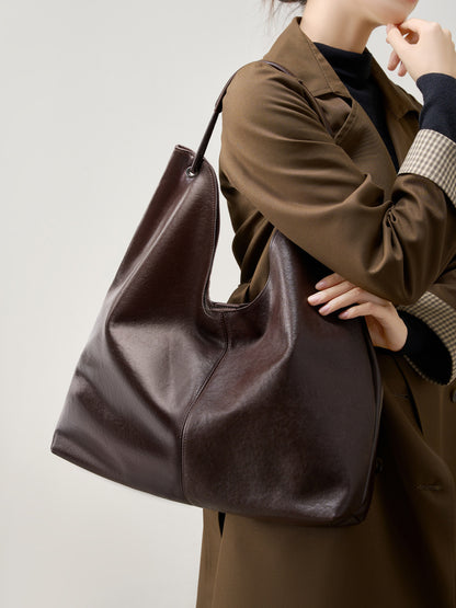 Brown hobo tote bag carried under the arm with a brown trench coat