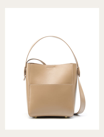 Apricot cowhide bucket crossbody bag with top handle on white background