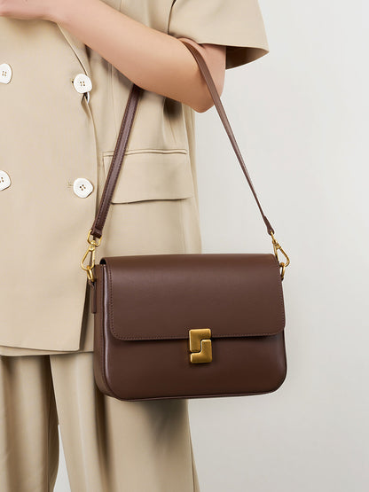 Coffee cowhide crossbody bag worn on shoulder with adjustable strap