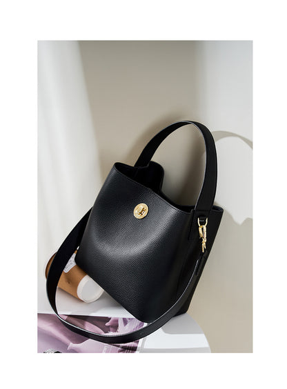Black bucket bag styled on table with magazine and bottle