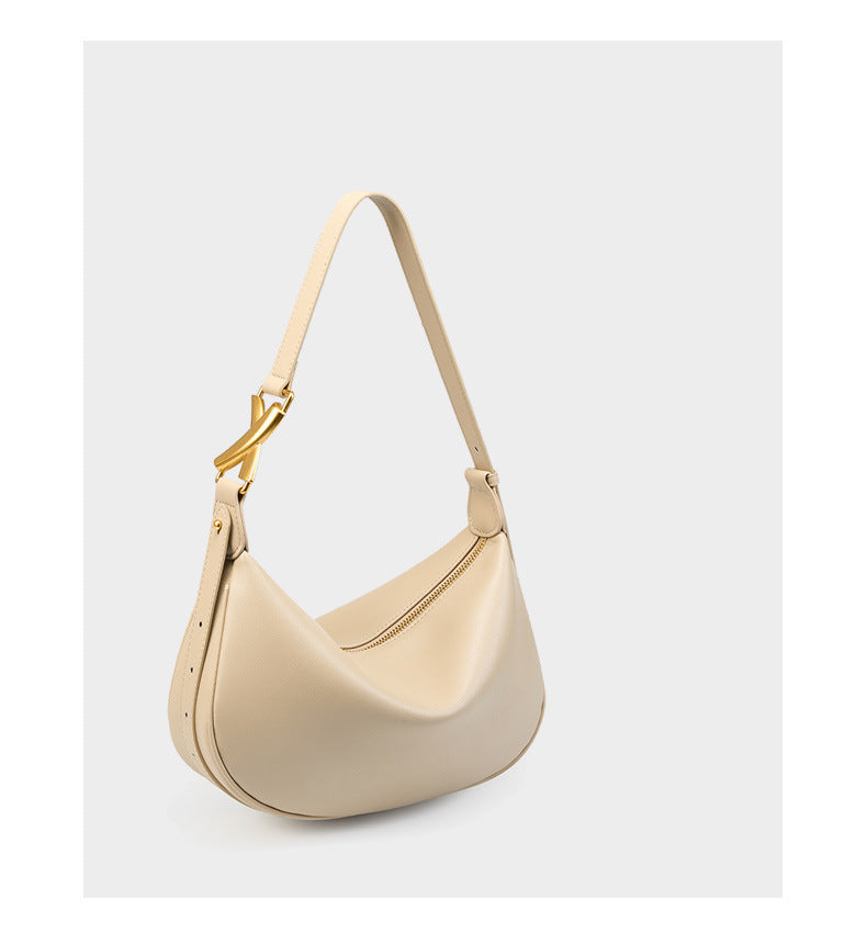 Off-white cowhide crescent underarm bag with gold-tone X buckle at three-quarter angle