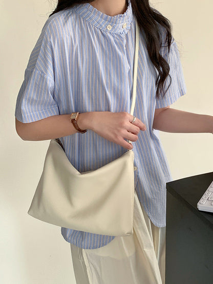 Cream hobo bag worn crossbody with a blue striped shirt