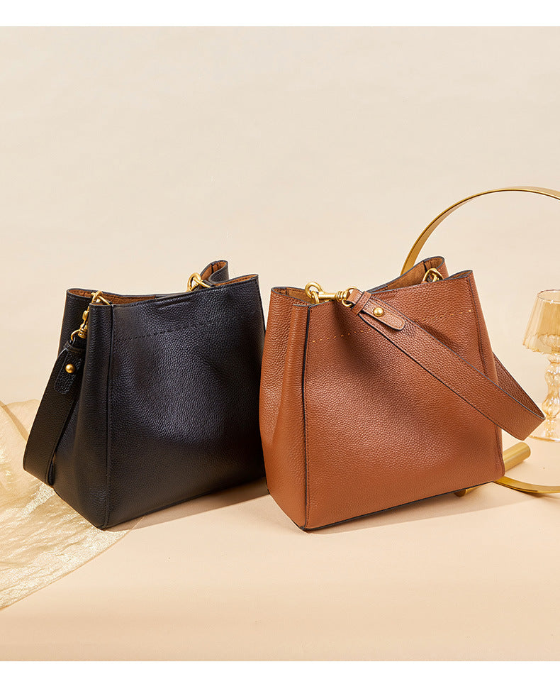 Black and tan leather bucket totes with antique gold hardware on display