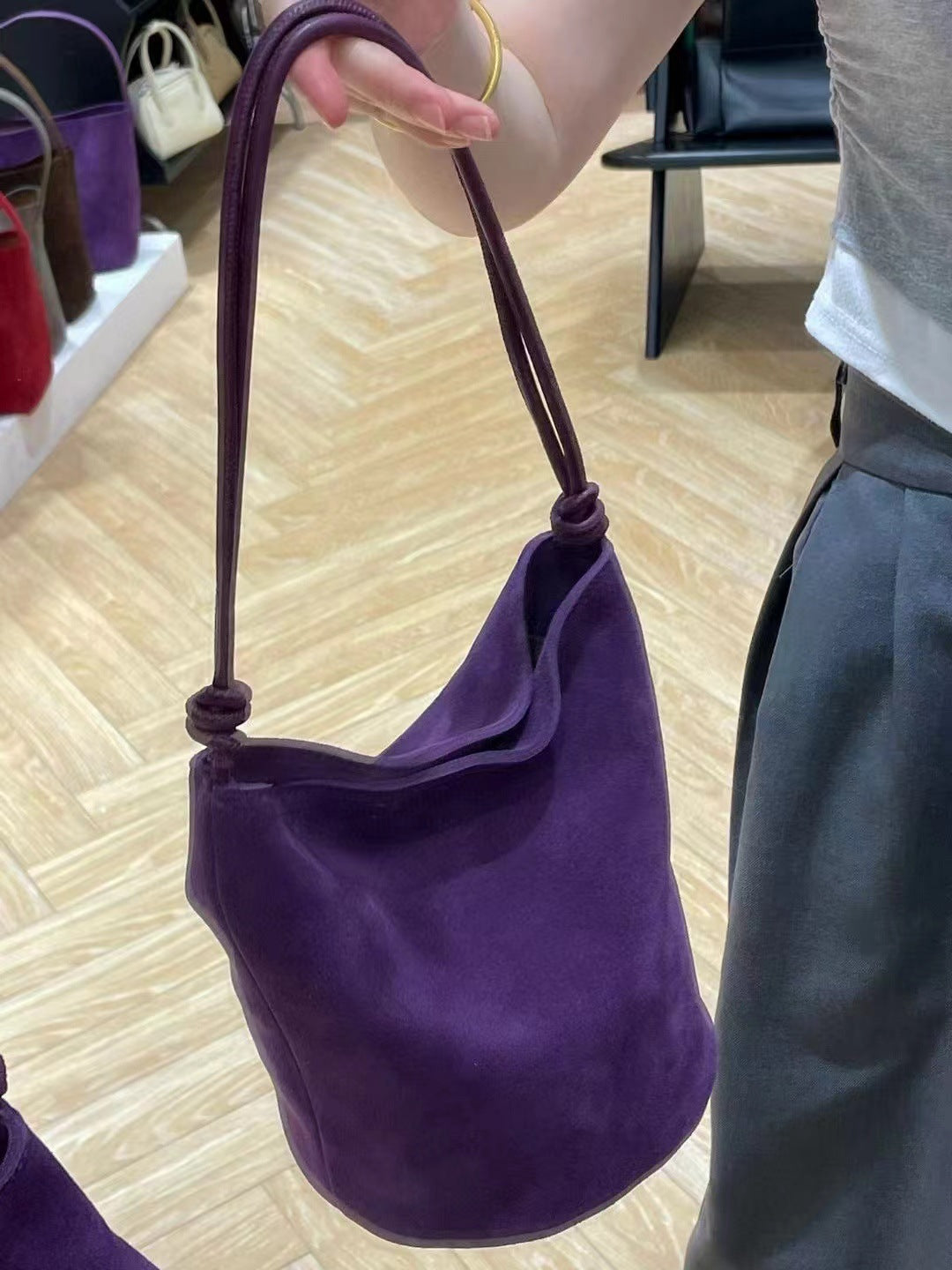 Purple bag held by its strap to show the side profile