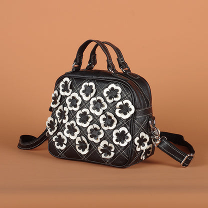Black and white cowhide shoulder bag with raised floral appliques