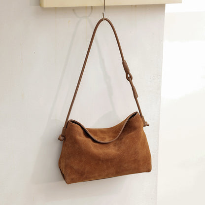 Brown suede cowhide bag showing its curved top and single strap