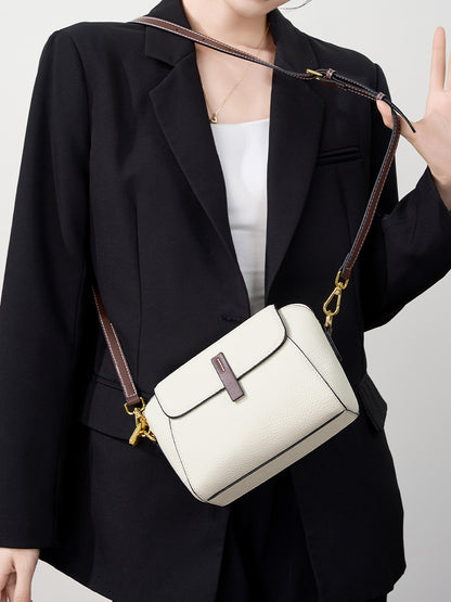 Ivory shell crossbody bag worn crossbody over a black blazer