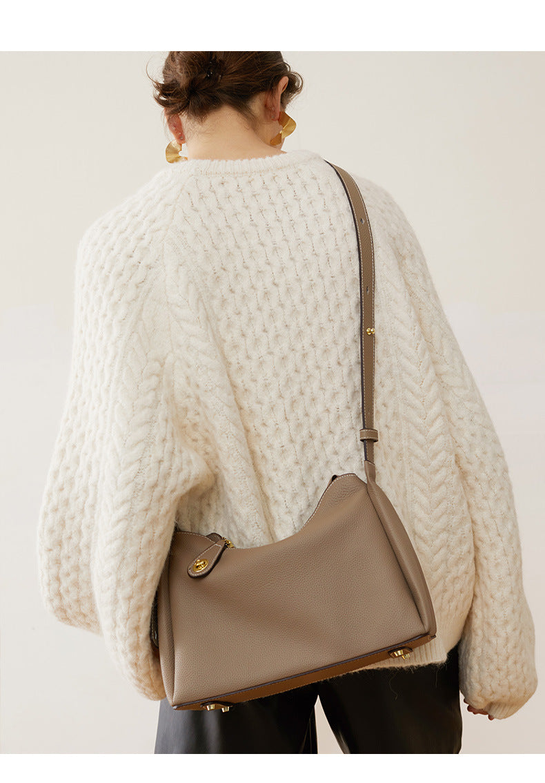 Model carrying light gray leather shoulder bag on shoulder in cream knit