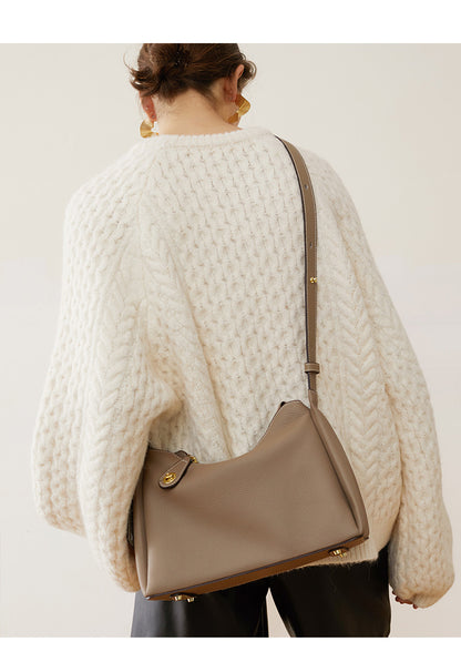 Model carrying light gray leather shoulder bag on shoulder in cream knit
