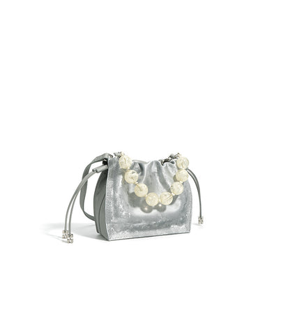 Close-up of silver mini bucket bag with beaded handle and metallic hardware