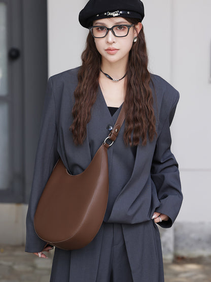 Brown crescent bag styled crossbody on a model