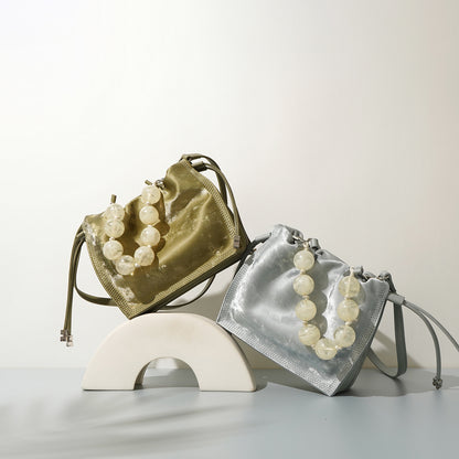 Champagne and silver mini bucket bags styled together on a curved display