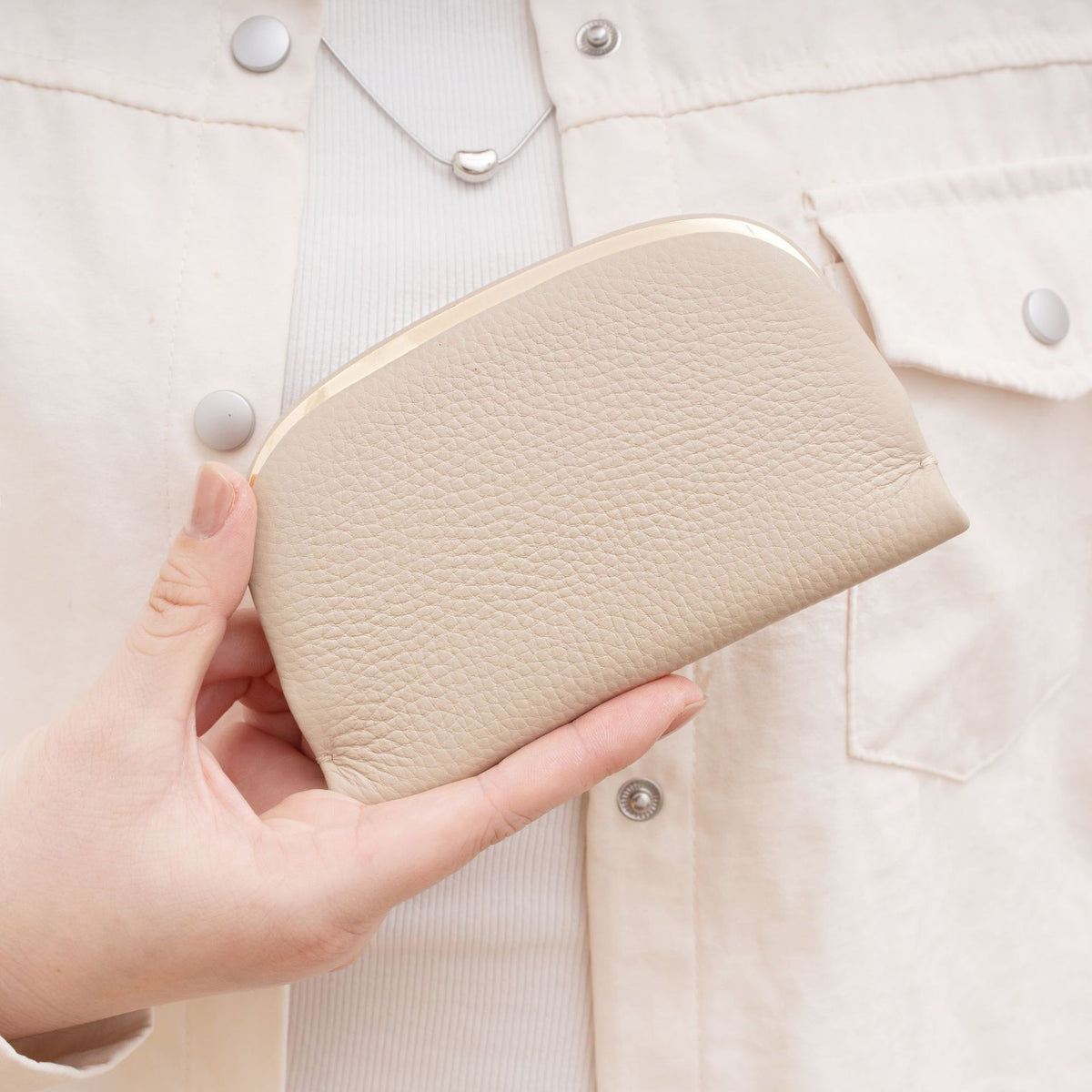 Ivory textured cowhide coin purse held in hand