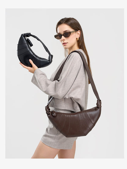 Model holding black crescent bag while wearing coffee version crossbody